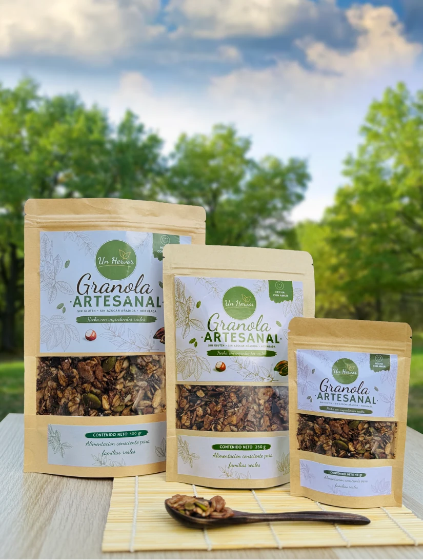 Tres presentaciones de granola artesanal Un Hervor sobre una mesa, rodeadas de naturaleza